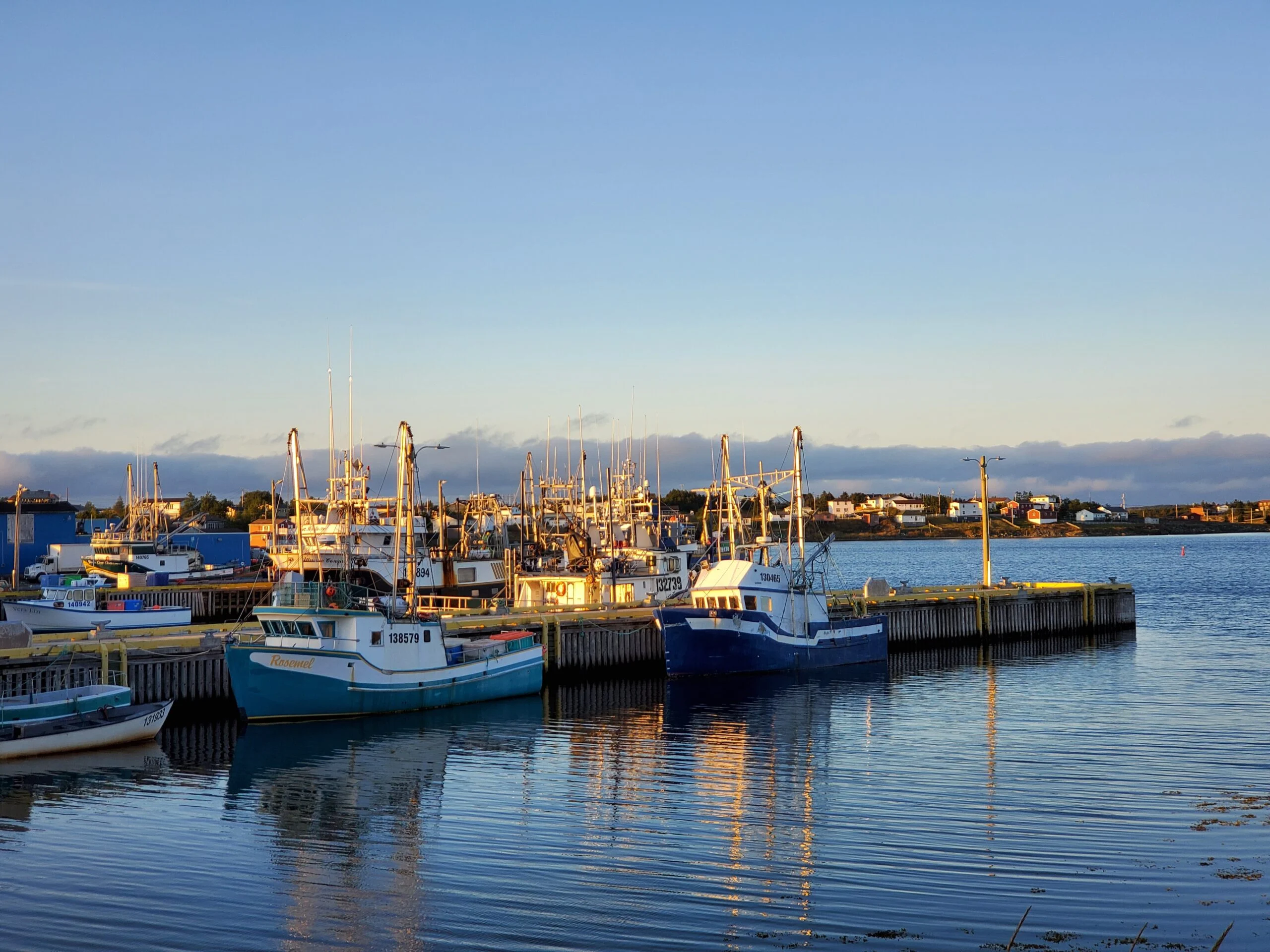 Fishing boats docked at harbor at sunrise