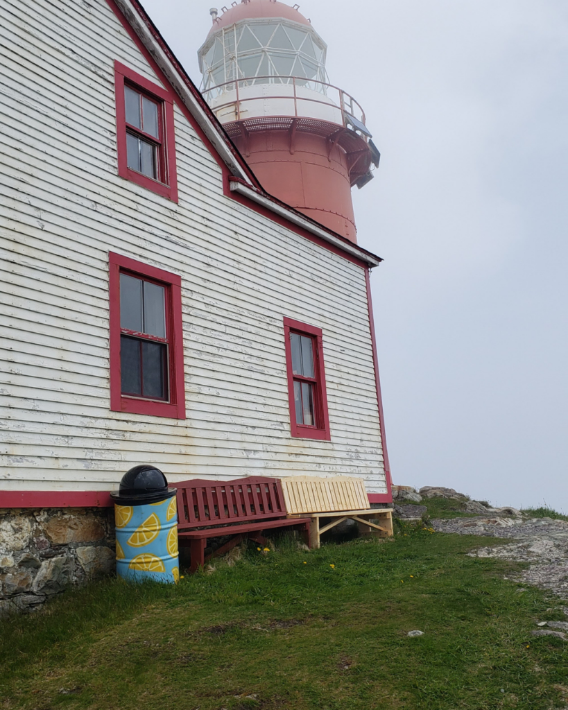 White lighthouse with red trim and bench